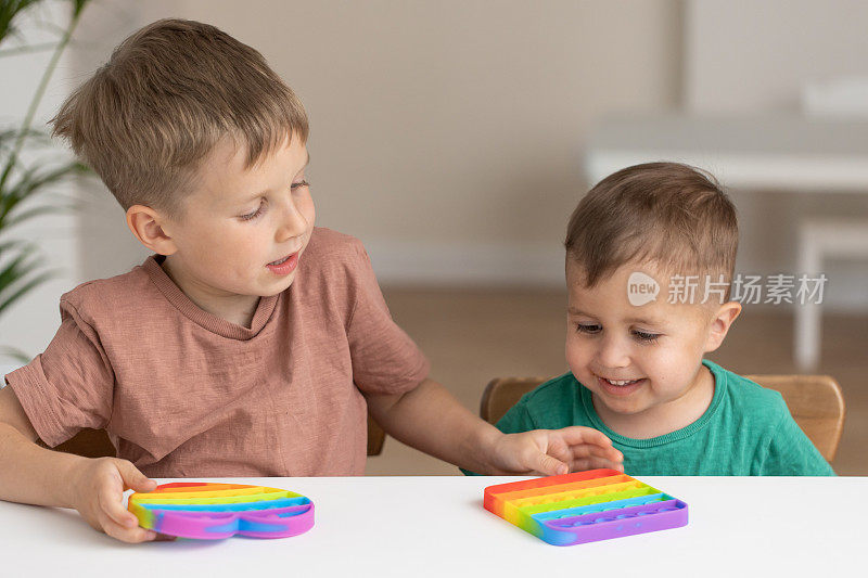 可爱的孩子们玩着Pop It坐立不安。新的抗压力游戏-推泡泡灵活烦躁。用于放电、儿童发育的感官玩具